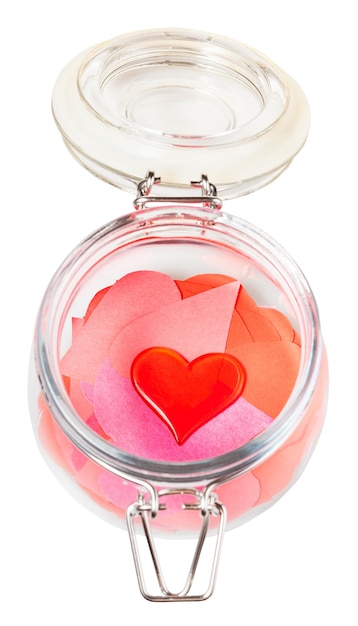 Glass heart on pile of paper hearts in open jar