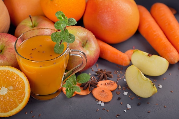 Glass of homemade juice or smoothie, fruits and vegetables. Fresh carrot, apple, pumpkin, orange, grapefruit on dark table. Healthy eating, food, dieting, detox and vegetarian concept.