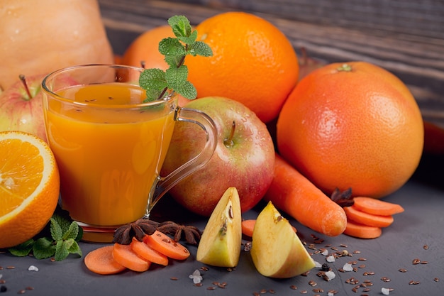 Glass of homemade juice or smoothie, fruits and vegetables. Fresh carrot, apple, pumpkin, orange, grapefruit on dark table. Healthy eating, food, dieting, detox and vegetarian concept.