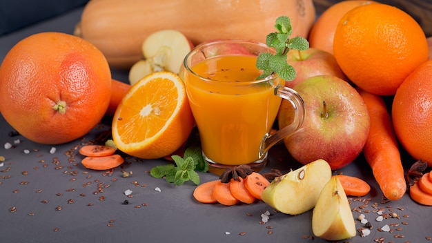 Glass of homemade juice or smoothie, fruits and vegetables. Fresh carrot, apple, pumpkin, orange, grapefruit on dark table. Healthy eating, food, dieting, detox and vegetarian concept.