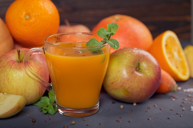 Glass of homemade juice or smoothie, fruits and vegetables. Fresh carrot, apple, pumpkin, orange, grapefruit on dark table. Healthy eating, food, dieting, detox and vegetarian concept.