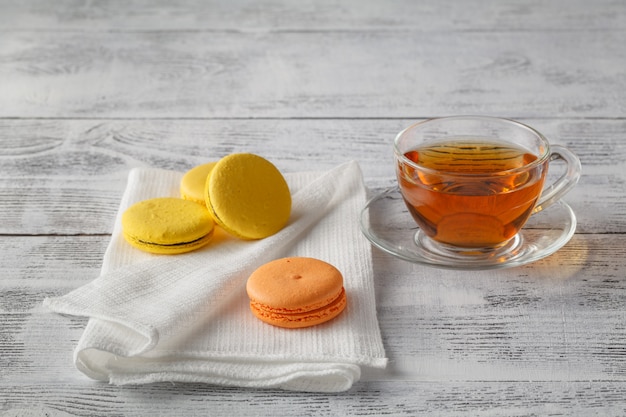 Glass hot cup of tea on a wooden table with macaroons