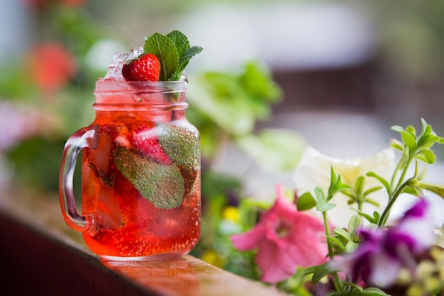 Glass of ice tea on background of flowers