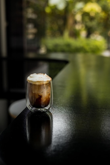 A glass of iced coffee is positioned on the countertop of a bar