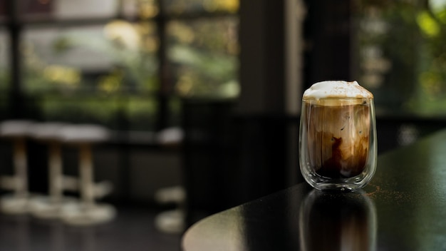 A glass of iced coffee is positioned on the countertop of a bar