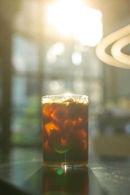 A glass of iced coffee sits on a bar counter.