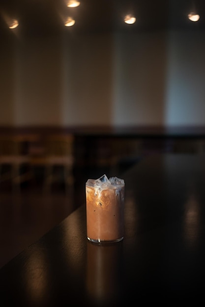 A glass of iced coffee sits on a bar counter.