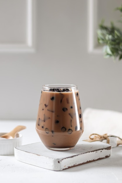 A glass of iced coffee sits on a book on a table.