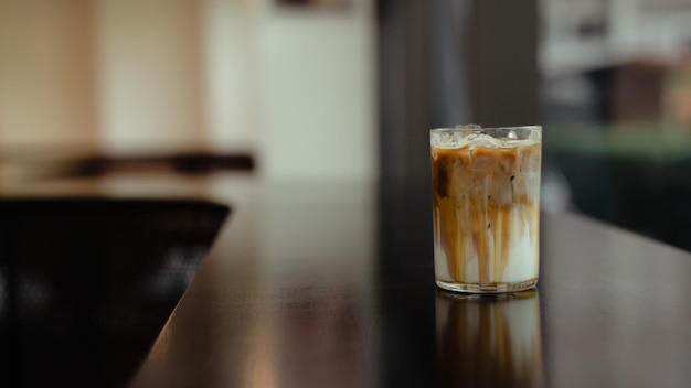 A glass of iced coffee sits on a counter.