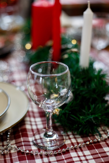 The glass is on a Christmas table decorated with a tablecloth candles and tinsel