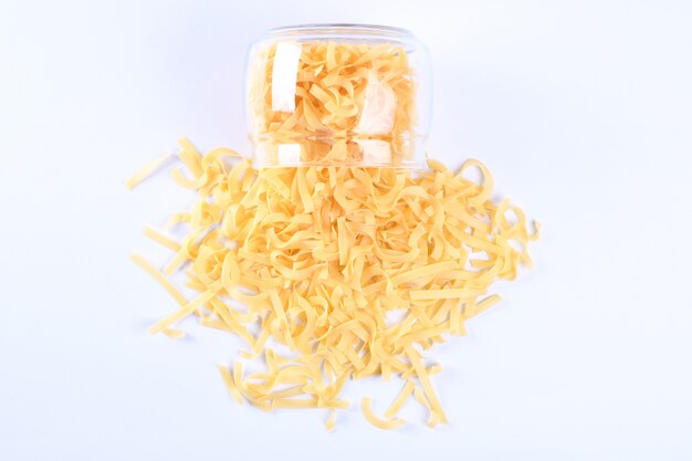 Glass jar filled with dry rotini yellow pasta isolated