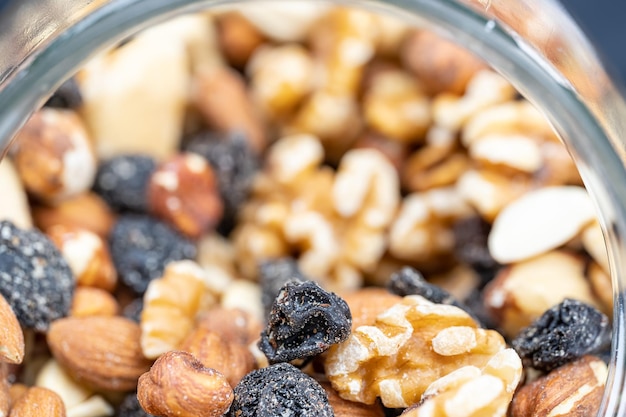 Glass jar full of assorted nuts with almonds hazelnuts cashews and raisins in a macro photograph shot