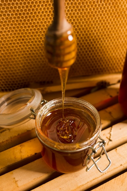 Glass jar full of honey with honey spoon