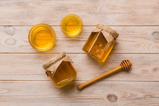 Glass jar of honey with wooden drizzler on colored background Honey pot and dipper high above Top view copy space