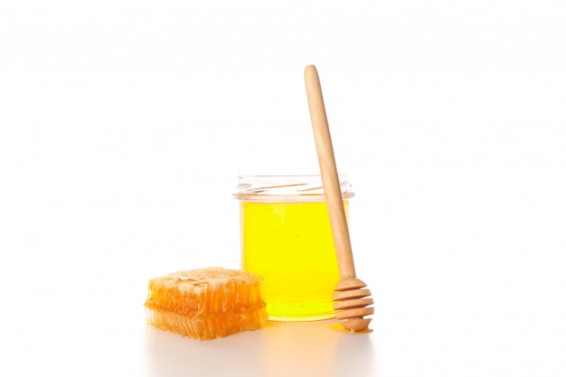 Glass jar, honeycomb and dipper isolated on white background