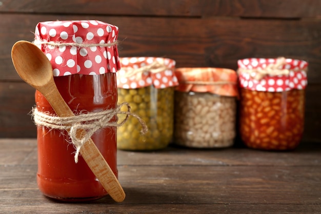 Glass jar of hot tomato sauce on wooden background