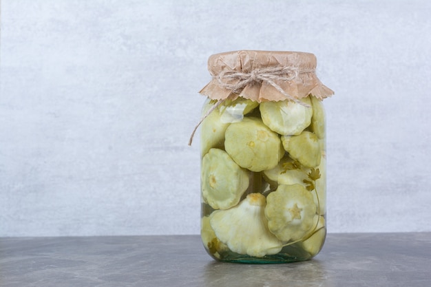 Glass jar of pickled vegetables placed on marble