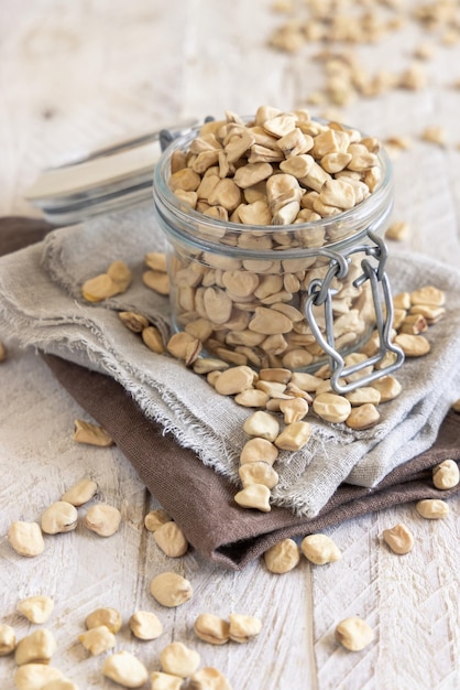 Glass jar of raw dry Grass pea on kitchen towel close up Italian legumes Cicerchia