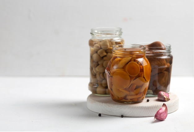 Glass jar with canned mushrooms with garlic and pepper.