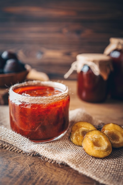 Glass jar with delicious homemade plum jam on table