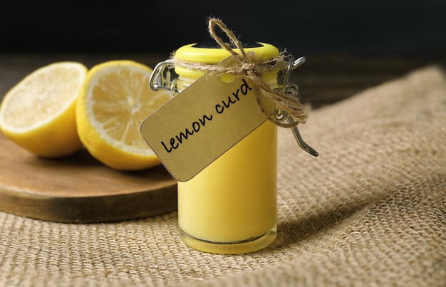 Glass jar with delicious lemon curd on table