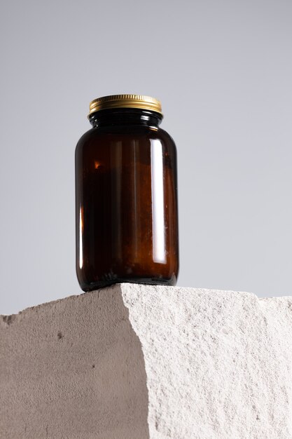 Glass jar with dietary supplement on cinder block close up