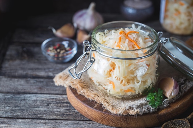 Glass jar with homemade sauerkraut on rustic wooden table