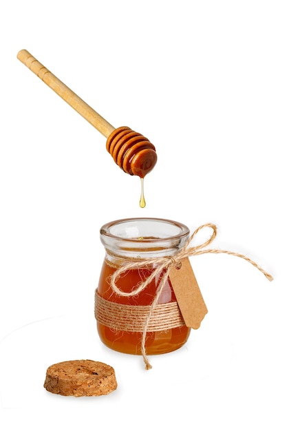 Glass jar with label for writing and honey dripping from dipper isolated on white background