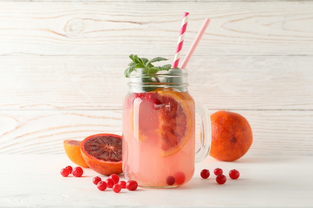 Glass jar with lemonade and ingredients on wooden surface