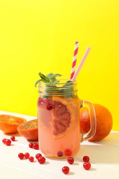 Glass jar with lemonade and ingredients on wooden table. Fresh drink