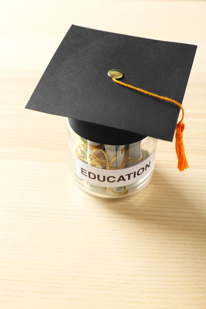 Glass jar with money for education on wooden table