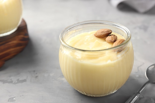 Glass jar with vanilla pudding with almond on table