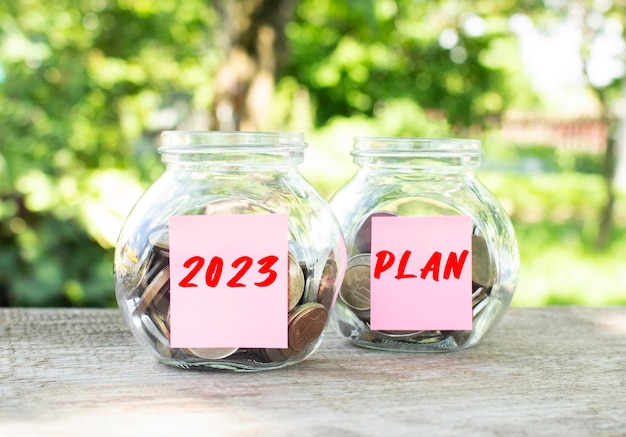 Glass jars with coins and the inscriptions  and plan stand on a wooden table investment budget