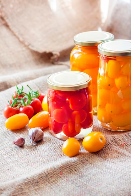 Glass jars with homemade pickled tomatoes, sealed with metal lid