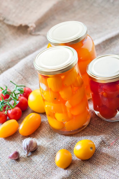 Glass jars with homemade pickled tomatoes, sealed with metal lid