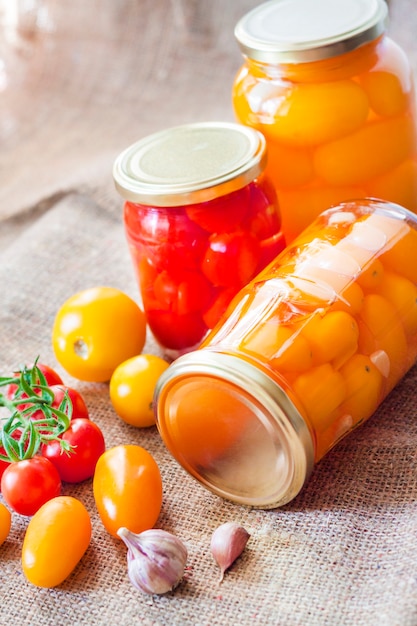 Glass jars with homemade pickled tomatoes, sealed with metal lid