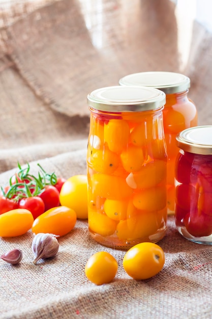 Glass jars with homemade pickled tomatoes, sealed with metal lid