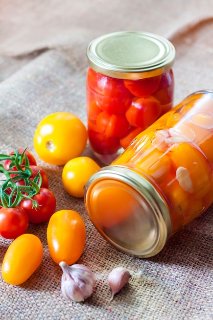 Glass jars with homemade pickled tomatoes, sealed with metal lid