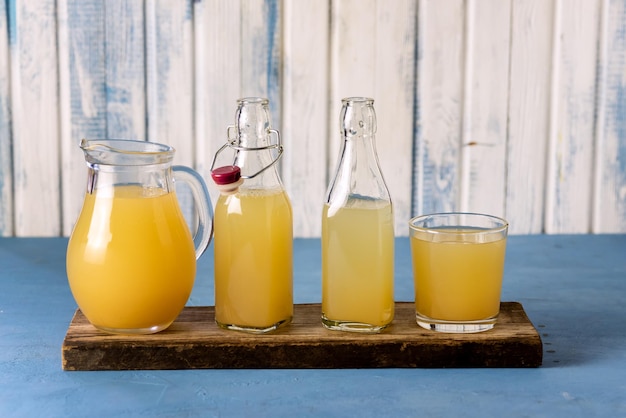 Glass Jug Bottles and Glass with Healthy Organic Apple Juice with Pulp on Wooden Tray Rustic