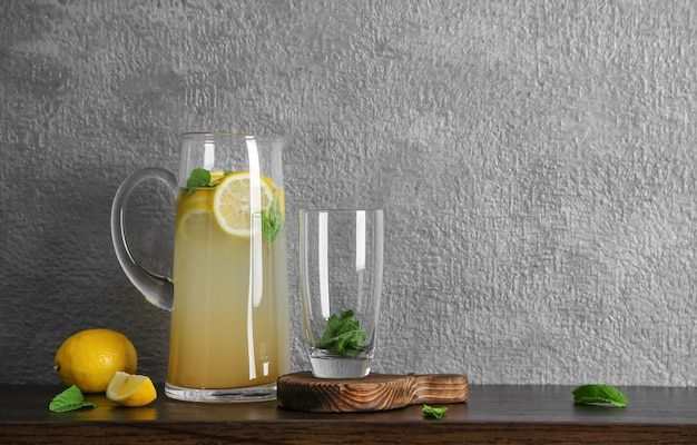 Glass jug with lemonade on wooden table