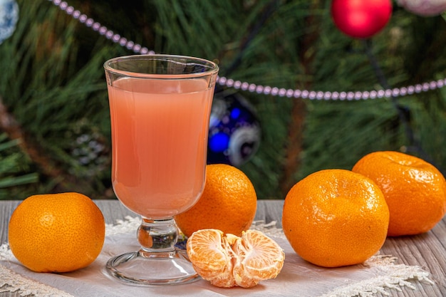 Glass of juice mandarins and a fir tree with Christmas ornaments