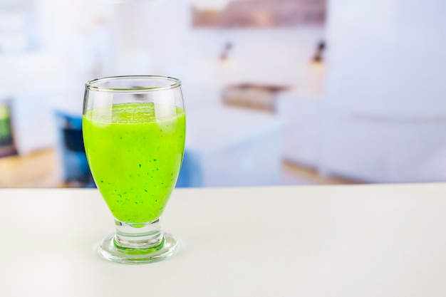 Glass of juice with cucumber and parsley on white table Detox cocktail of raw fruits and vegetables and lettuce and parsley the background is out of focus