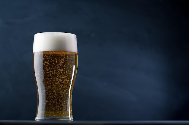 A glass of lager light beer on a dark background copy space