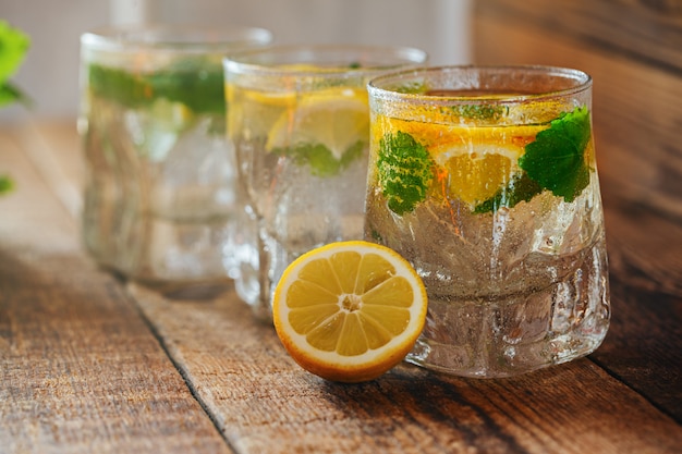 Glass of lemonade with fresh lemon and mint on wooden background