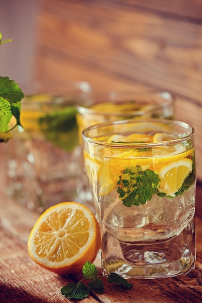 Glass of lemonade with fresh lemon and mint on wooden background