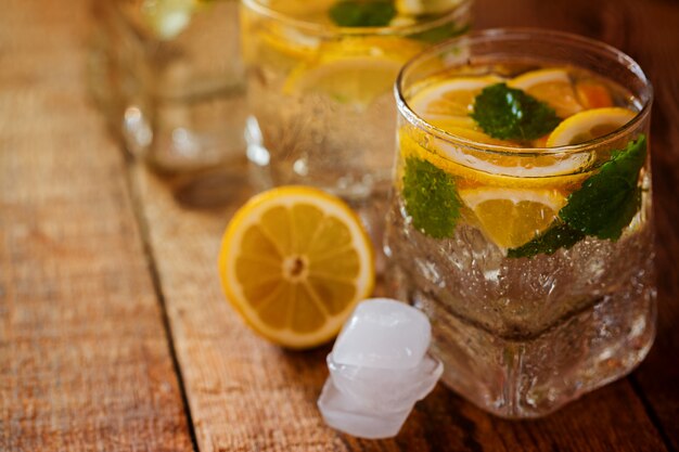 Glass of lemonade with fresh lemon and mint on wooden background