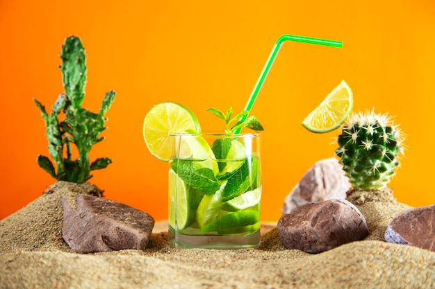 Glass of lemonade with lime and mint among the sand dunes and cacti