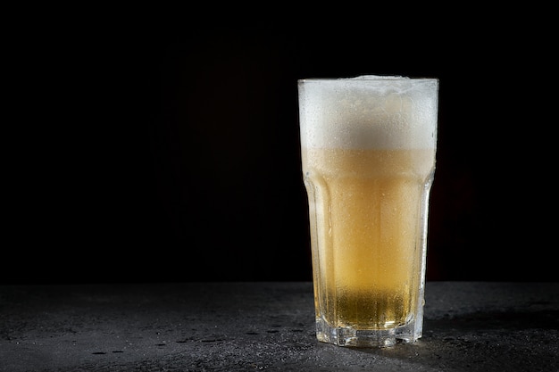 A glass of light beer on dark