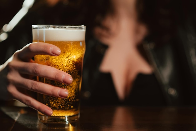 Glass of light beer lager with foam in the hand of a woman