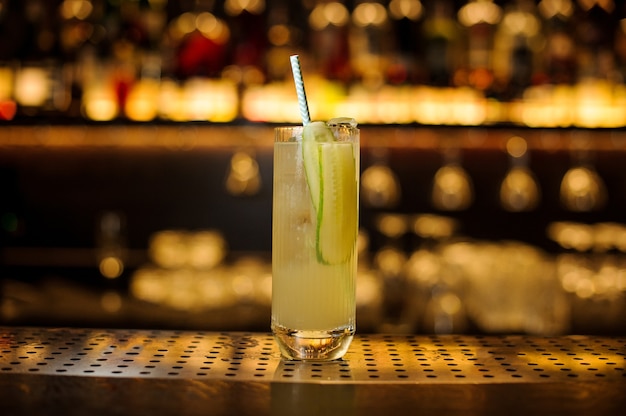 Glass of a Lynchburg lemonade cocktail with a cucumber on the wooden steel bar counter